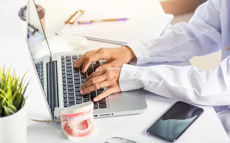 Dentist reviewing digital marketing stats on a laptop while patients wait, showing SEO charts, ads, and social media growth