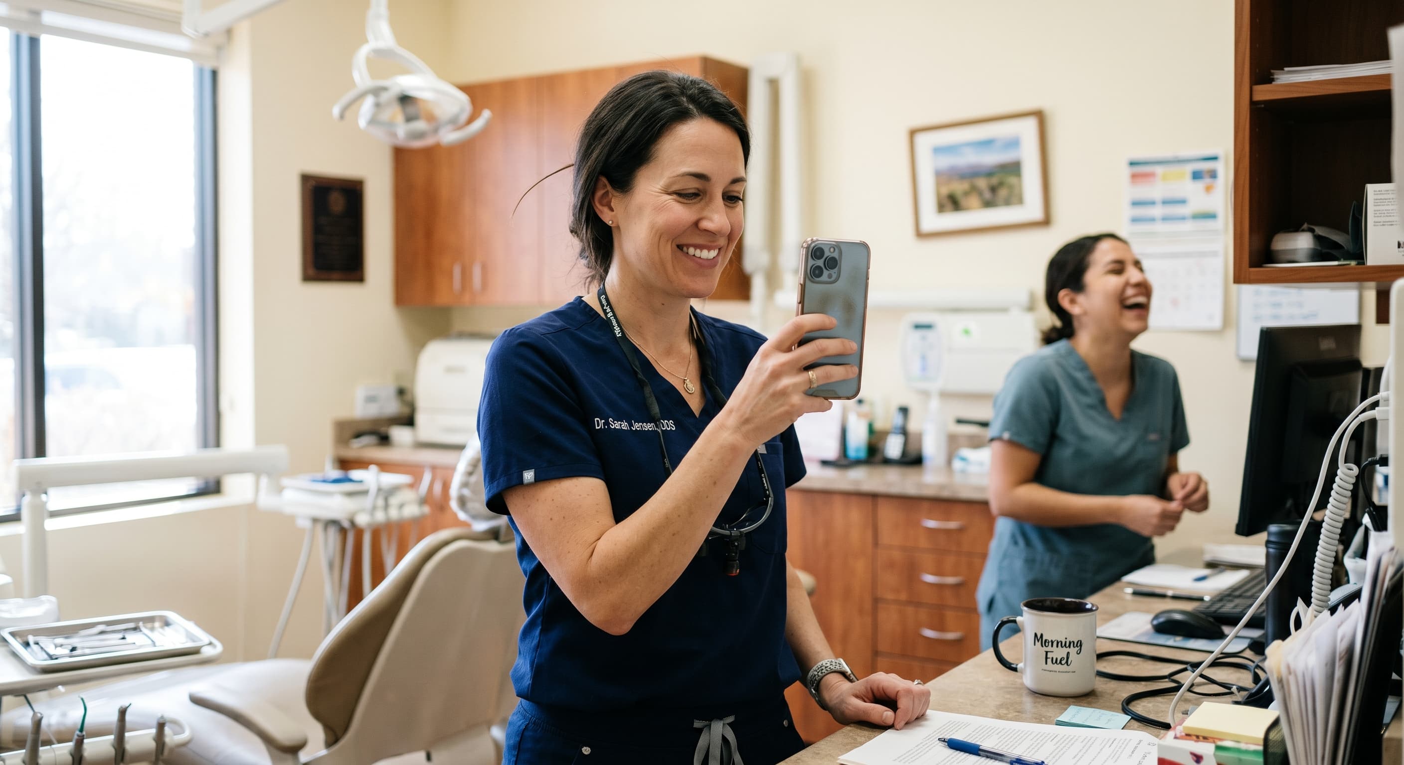 Dentist filming a short educational video in a modern dental office, smiling team behind, using phone for social media